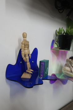 there is a small wooden figure on top of a blue shelf next to other items