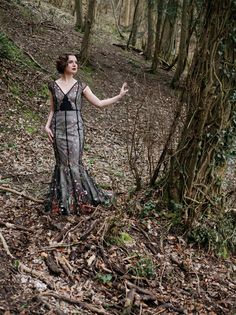 a woman standing in the woods with her hand out