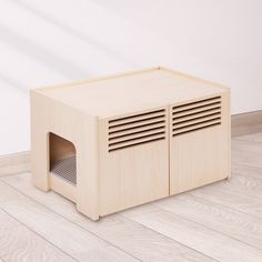 a small wooden litter box sitting on top of a hard wood floor next to a white wall