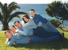 a group of people laying on top of each other in the grass next to water