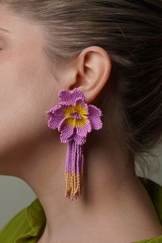 a close up of a person wearing earrings with flowers on the front and back of them