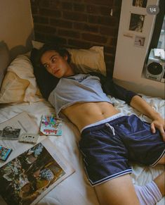 a man laying in bed with his shirt off and some magazines on the floor next to him