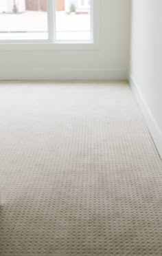 an empty room with a window and carpet