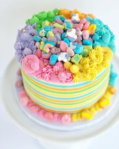 there is a multi layer cake decorated with colorful icing and sprinkles