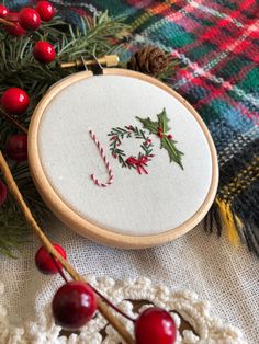 a close up of a cross stitch on a table with christmas decorations and yarns