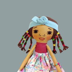 a doll with long hair wearing a dress and a blue headband is standing in front of a gray background