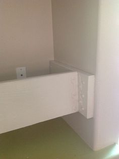 the corner of a room that is painted white and has an electrical outlet in it