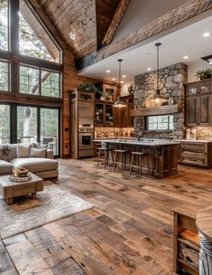 a large open concept kitchen and living room with wood flooring, stone walls, exposed beams, and vaulted ceiling