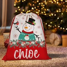 a bag with a snowman on it sitting in front of a christmas tree