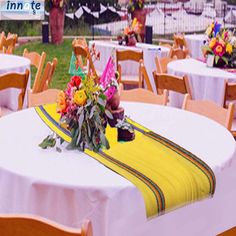 an outdoor event with tables and chairs covered in white tablecloths, decorated with colorful flowers