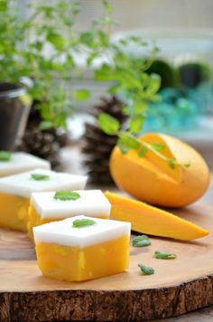 pieces of cheese sitting on top of a wooden cutting board next to plants and pine cones