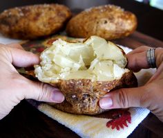 a person holding up a piece of food on top of a towel next to some potatoes