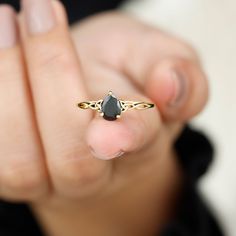 a woman is holding her hand up to the camera with a black diamond ring on it