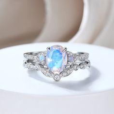 an opal and diamond ring is displayed on a white surface with other jewelry items