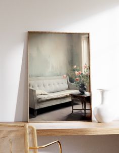 a white couch sitting next to a table with a vase and chair on top of it