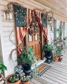 potted plants line the front porch of a house with an american flag on it