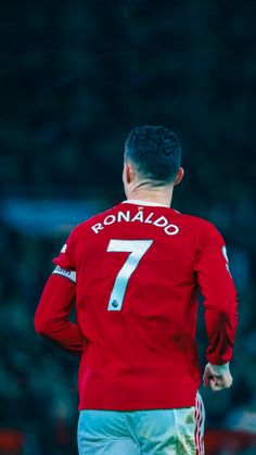 a man in red shirt standing on top of a soccer field with his back to the camera