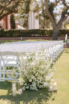 the aisle is lined with white flowers and candles for an outdoor ceremony in front of a building