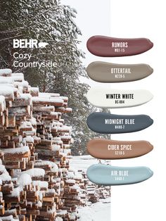 several different colors of wood stacked on top of each other in front of snow covered trees