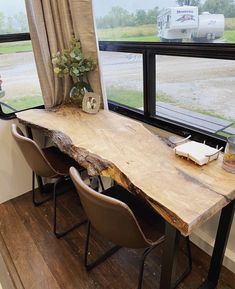 a wooden table with two chairs next to it and a window in the back ground