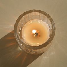 a lit candle sitting on top of a table next to a white wall and floor