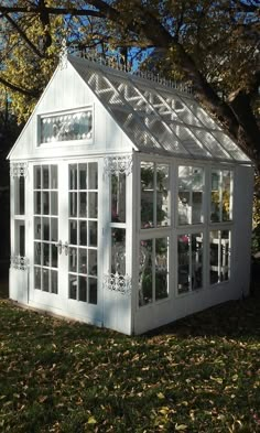 a small white house sitting on top of a lush green field next to a tree