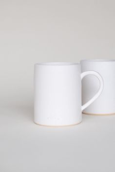 two white coffee mugs sitting next to each other