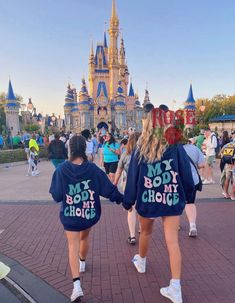 two girls in matching sweatshirts walk down the street with their arms around each other