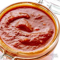 a jar filled with red sauce sitting on top of a table