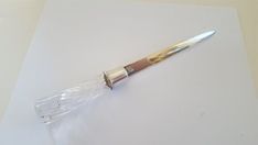 a silver and gold pen sitting on top of a piece of white paper next to a knife