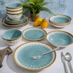 a table topped with plates and bowls next to a vase filled with lemon wedges