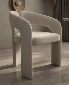 a white chair sitting on top of a floor next to a wall mounted clock in a living room