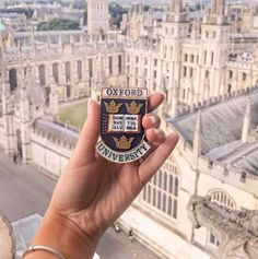 a person holding up a badge in front of a cityscape with the words oxford on it