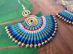 a pair of blue and red beaded earrings sitting on top of a wooden table