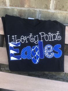 PRODUCTION TIME: production time is 2-3 weeks plus shipping. PLEASE MAKE SURE THIS WORKS FOR YOU BEFORE PLACING YOUR ORDER. Love your school! Customize your school spirit! This listing for the name of your school. Appliqué letters with coordinating fabrics. Here are the details I need to customize your order: 1) Top name...example Eaton 2) Bottom name....example Eagles 3) School colors/Fabric colors. I will use as many different fabrics that coordinate with your school colors. 4) Any other detai School Spirit T-shirt With Embroidered Graphics For College, College School Spirit T-shirt With Custom Embroidery, College T-shirt With Embroidered Graphics For School Spirit, College T-shirt With Custom Embroidery For School Spirit, School Spirit T-shirt With Embroidered Graphics, School Spirit T-shirt With Team Name For School Events, Blue School Spirit T-shirt, Blue T-shirt With Embroidered Graphics For School Spirit, Blue Embroidered College T-shirt