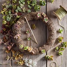 a clock made out of fake succulents on a wooden table with yarn and needles