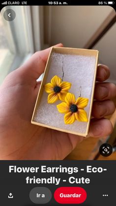 a person holding up a box with some yellow flowers in it's earwires