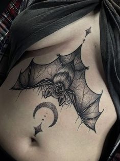 a woman's stomach with a bat and crescent tattoo on it