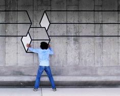 a man standing in front of a concrete wall with arrows drawn on it and pointing to the side