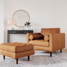 a living room with a chair, ottoman and mirror on the wall next to it