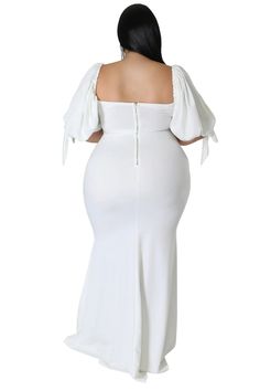 a woman in a white dress with her back turned to the camera, wearing an off shoulder