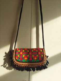 A very stylish and eye- catching sling bag for women is handmade from vintage and authentic textiles. This bag looks attractive with a foldover shape and hidden magnetic fastening. This bag comes with a strap to use for crossbody or shoulder style wearing. There are two zippered compartments inside to carry your valuables. This sling bag is sewn together and embellished with exquisite embroidery.The materials of this bag are vintage which are collected over the course of many years by nomadic tr Bohemian Clutch Bag With Tassels, Bohemian Tassel Clutch Bag, Bohemian Clutch Shoulder Bag With Tassels, Bohemian Tassel Clutch Shoulder Bag, Bohemian Multicolor Clutch Pouch, Bohemian Clutch Shoulder Bag For Festivals, Black Bohemian Pouch Clutch, Bohemian Black Pouch Clutch, Bohemian Clutch With Handwork