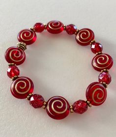 "Beautiful holiday red Czech glass spiral beads and ruby red shimmering Picasso glass with antique gold accents on a stretch bracelet. Matte red and gold puffy spiral coin beads are 12 x 14 mm with translucent Picasso glaze. Alternating 8 mm ruby red beads with gold Picasso finish. Lovely beads are accented with antique gold plated daisies and beaded spacers by Tierracast made in USA. Made to order in your size. Bracelet is made on professional stretch elastic. Example is about 7\" and fits a 6\ Gold Stretch Bracelet, Handmade Jewlery, Red Bracelet, Bracelet Christmas, Diy Jewelry Unique, Ball Bracelet, Dope Jewelry, Gold Charm Bracelet, Spiral Earrings