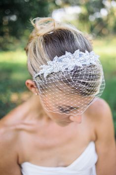 a woman with a veil on her head wearing a wedding dress and hair combs