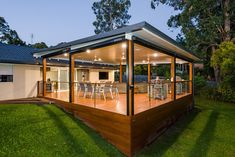 a house with wooden decking and an outdoor kitchen on the top floor is lit up at night