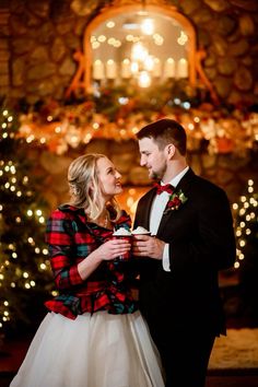 a man and woman standing next to each other in front of a christmas tree with lights