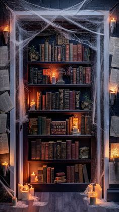 a book shelf with candles and books on it in front of a spider net hanging from the ceiling