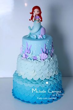 a blue and white cake with a little mermaid on top