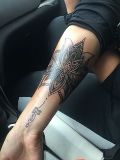 a person sitting in a car with a tattoo on their arm