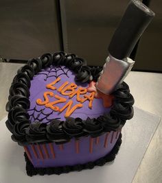 a purple and black heart shaped cake with a knife stuck in it